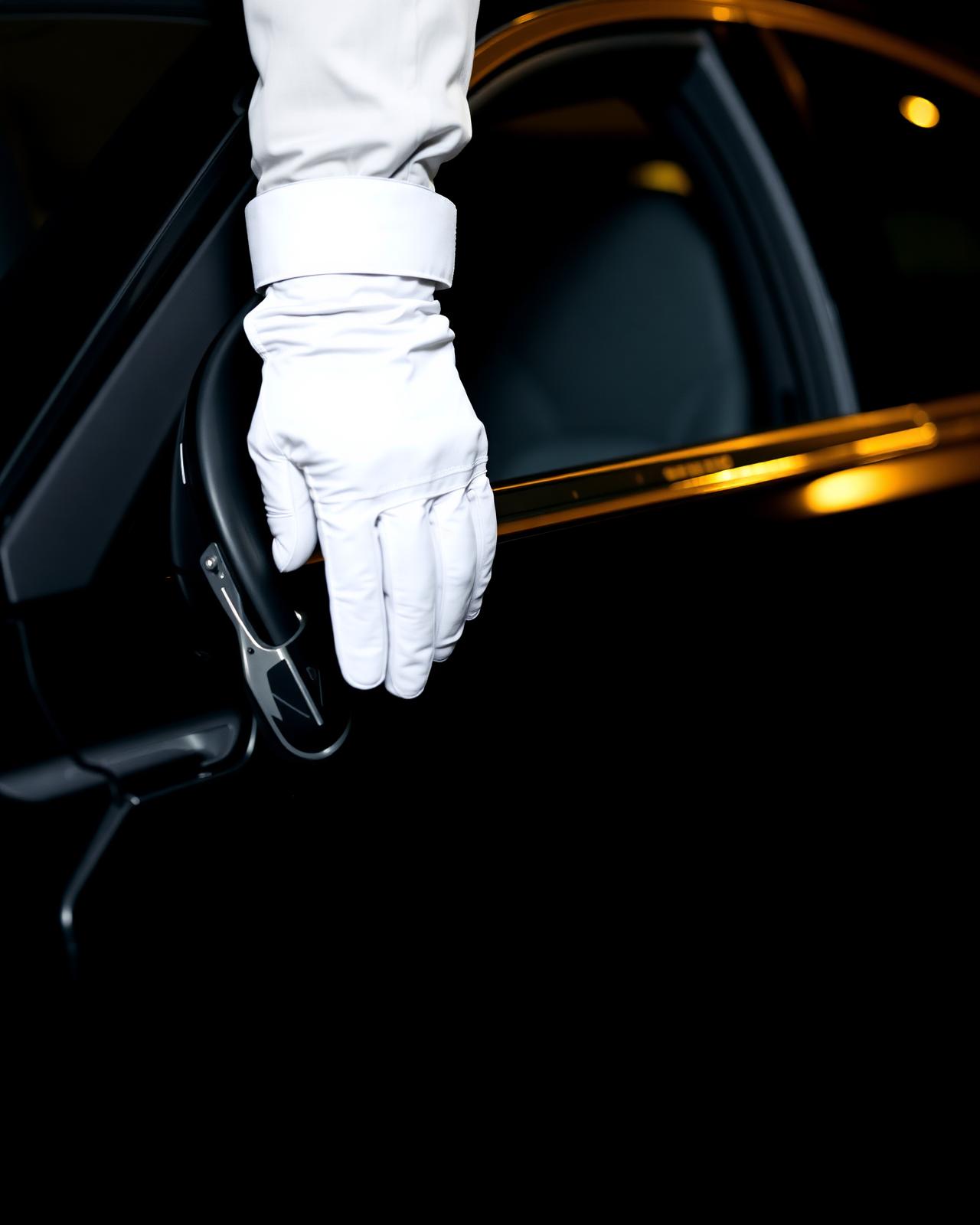 Chauffeur in white gloves opening the door of a luxury sedan